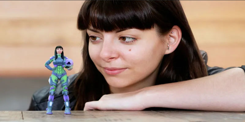 A woman with a 3D printed action figure of herself